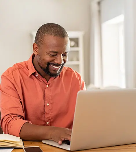 man sitting at table using laptop computer
